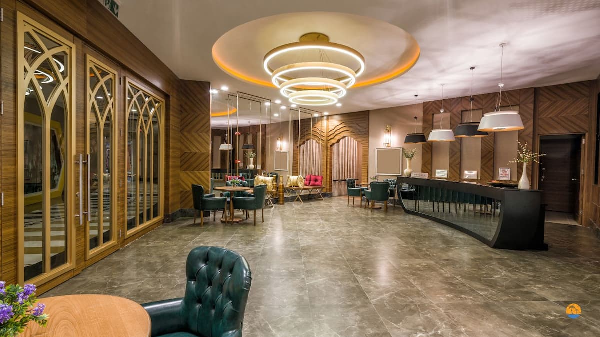 Nowoczesne wnętrze hotelowego lobby z recepcją, złotymi zdobieniami, stylowymi lampami i eleganckimi fotelami