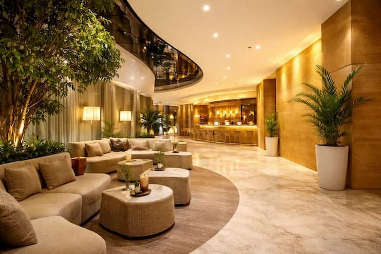 Przestronne lobby hotelowe w jasnych barwach z nowoczesnymi sofami i oświetleniem