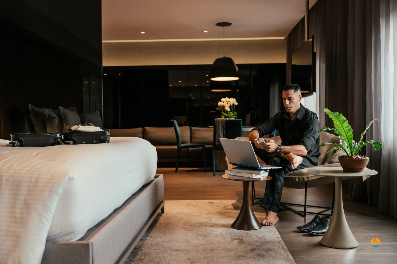 Pokój hotelowy z biurkiem, laptopem i strefą wypoczynkową w ciepłym oświetleniu