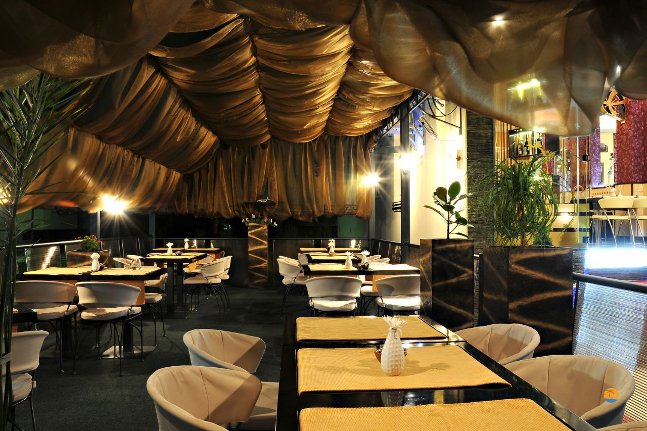 Elegancka restauracja hotelowa z miękkim oświetleniem i złotymi zasłonami na suficie