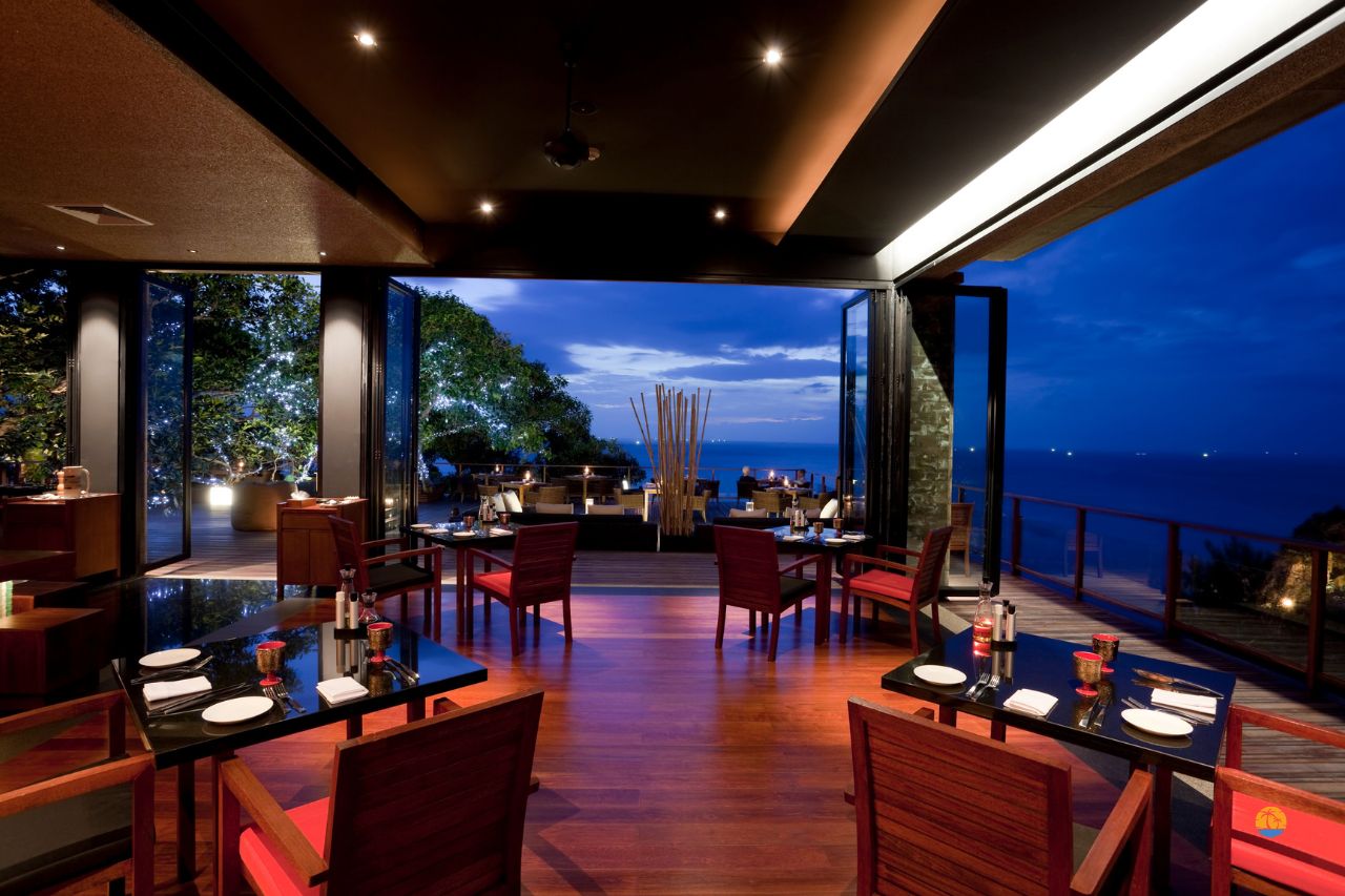 Restauracja z tarasem i widokiem na morze, ustawione stoliki przy zachodzie słońca